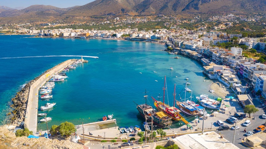 Bovenaanzicht van de haven van Kreta met een stralend zonnetje en azuurblauw water