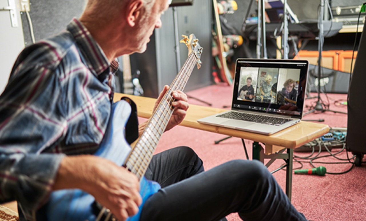 Opa Jaap speelt gitaar terwijl zijn kleinkinderen via de laptop in beeld zijn